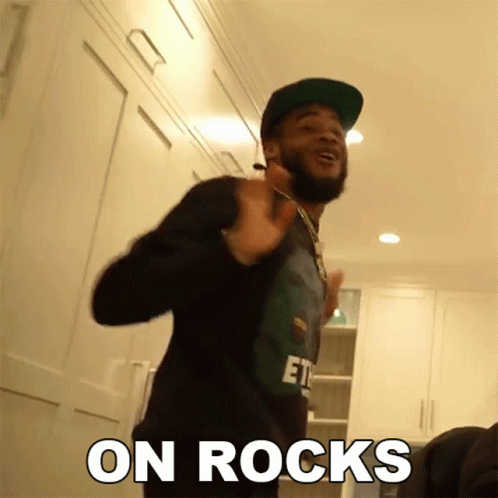 A Man With A Beard Wearing A Hat And A Shirt That Says " On Rocks " On It GIF