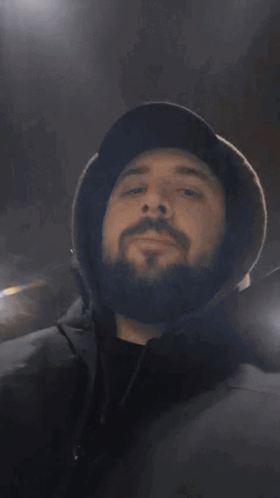 A Man With A Beard Wearing A Hat Covering His Mouth With His Hands GIF