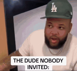 A Man With A Beard Wearing A La Hat Is Sitting In Front Of A Computer . GIF