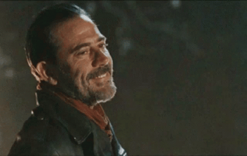 A Man With A Beard Wearing A Leather Jacket And Scarf Is Smiling . GIF