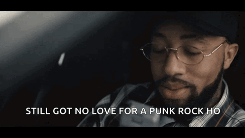 A Man With A Beard Wearing A Plaid Shirt And A Baseball Cap Says " Still Got No Love For A Punk Rock Ho " GIF