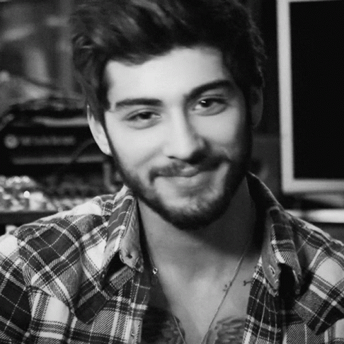 A Man With A Beard Wearing A Plaid Shirt Is Smiling In A Black And White Photo GIF
