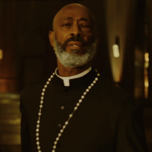 A Man With A Beard Wearing A Priest Collar And A Necklace GIF