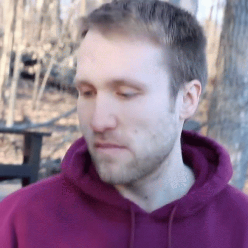 A Man With A Beard Wearing A Purple Hoodie Is Looking Down GIF