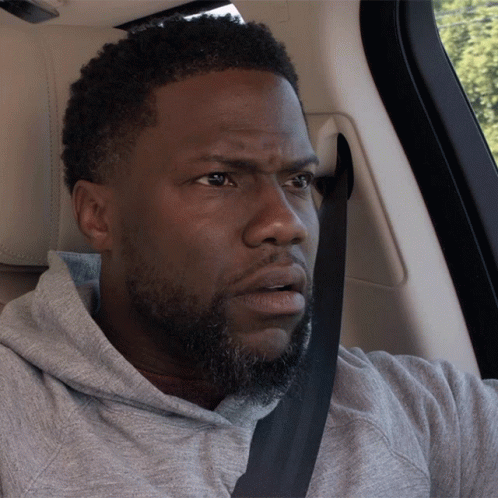 a man with a beard wearing a seat belt looks surprised