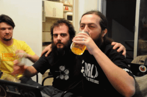 A Man With A Beard Wearing A Shirt That Says Erl Drinks From A Glass GIF