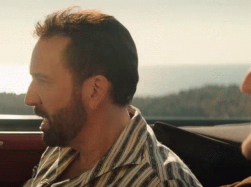 A Man With A Beard Wearing A Striped Shirt Is Sitting In The Back Seat Of A Car GIF