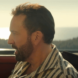 A Man With A Beard Wearing A Striped Shirt Looks To The Side GIF