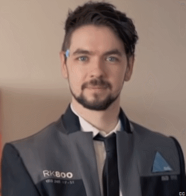 A Man With A Beard Wearing A Suit And Tie Is Looking At The Camera . GIF
