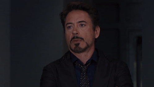 A Man With A Beard Wearing A Suit And Tie Looks At The Camera GIF