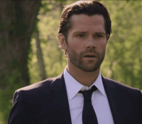 A Man With A Beard Wearing A Suit And Tie Looks Surprised GIF