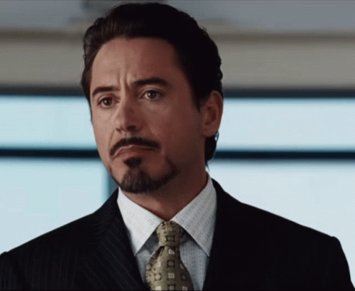 A Man With A Beard Wearing A Suit And Tie Looks To The Side GIF