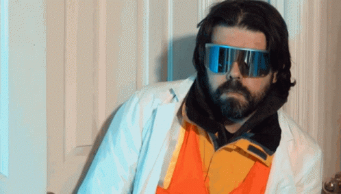 A Man With A Beard Wearing A White Coat And Sunglasses GIF