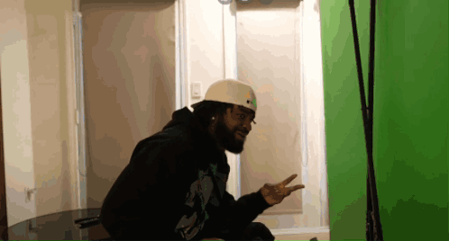 A Man With A Beard Wearing A White Helmet And A Black Hoodie GIF