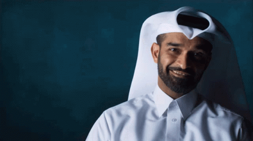 A Man With A Beard Wearing A White Shirt And A Scarf Covering His Face GIF