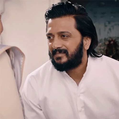 A Man With A Beard Wearing A White Shirt Is Smiling GIF
