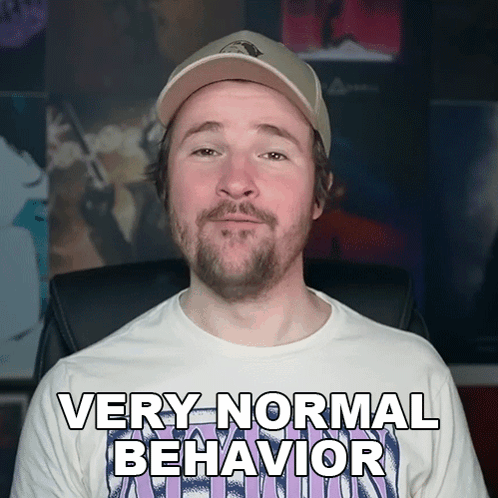 A Man With A Beard Wearing A White Shirt That Says Very Normal Behavior GIF
