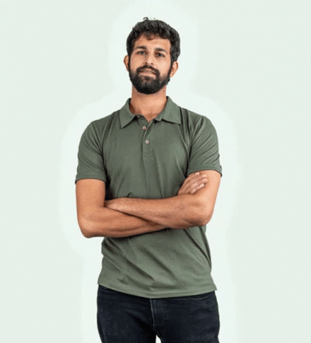 A Man With A Beard Wearing A Yellow Polo Shirt With His Hands In His Pockets GIF