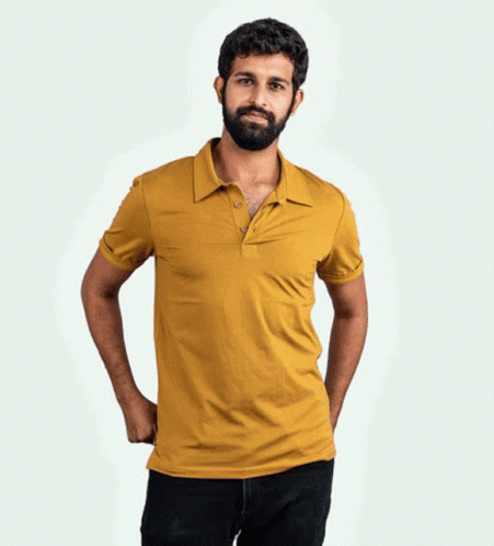 A Man With A Beard Wearing A Yellow Polo Shirt With His Hands In His Pockets GIF