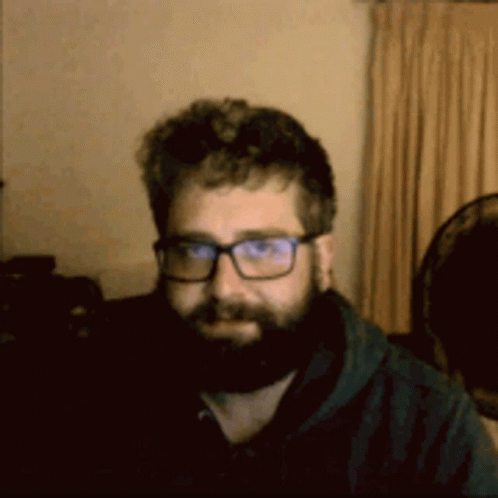 A Man With A Beard Wearing Glasses And A Black Shirt GIF
