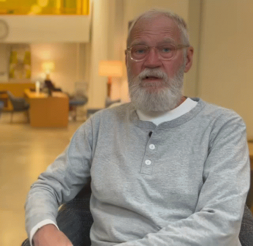 A Man With A Beard Wearing Glasses And A Grey Shirt Gives A Thumbs Up GIF
