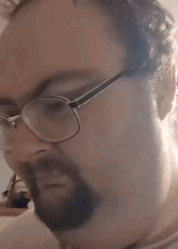 A Man With A Beard Wearing Glasses Is Making A Funny Face . GIF