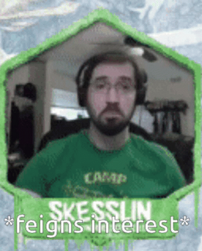 A Man With A Beard Wearing Headphones And A Green Shirt With The Words Skesslin Feigns Interest GIF