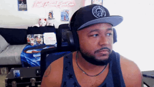 A Man With A Beard Wearing Headphones And A Hat Is Sitting In Front Of A Computer . GIF