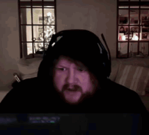 A Man With A Beard Wearing Headphones And A Hooded Jacket Is Laying In A Bed . GIF