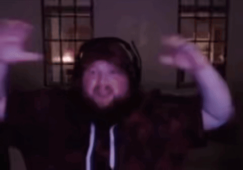A Man With A Beard Wearing Headphones And A Hoodie Is Dancing In A Dark Room GIF