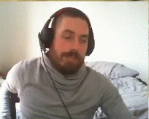 a man with a beard wearing headphones is sitting in front of a computer .