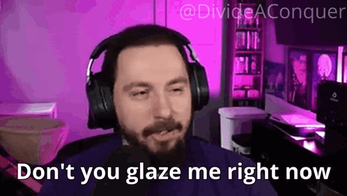 A Man With A Beard Wearing Headphones Is Sitting In Front Of A Microphone In A Purple Room . GIF
