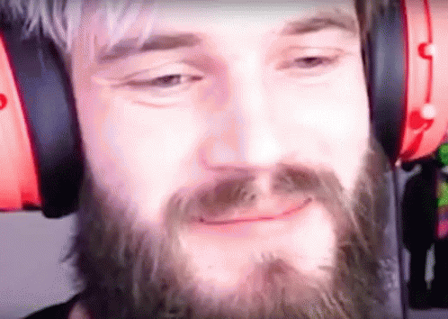A Man With A Beard Wearing Headphones Is Smiling . GIF