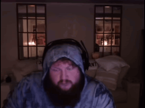 A Man With A Beard Wearing Headphones Stands In Front Of A Sign That Says Part My Pant GIF