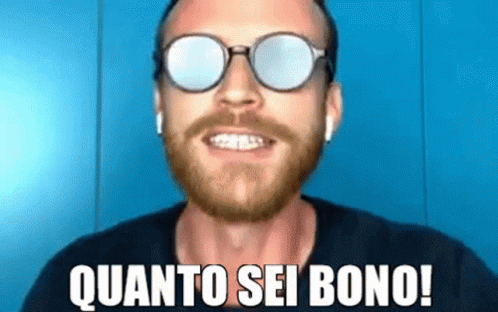 a man with a beard wearing sunglasses and ear buds is smiling and saying quanto sei bono !