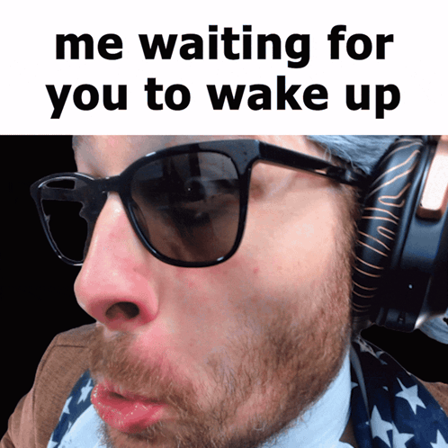 a man with a beard wearing sunglasses and headphones with the caption " me waiting for you to wake up "