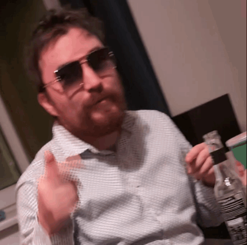 A Man With A Beard Wearing Sunglasses Holds A Bottle GIF