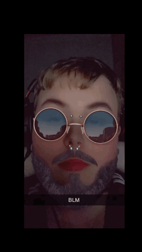 A Man With A Beard Wearing Sunglasses With A Reflection Of Mountains GIF