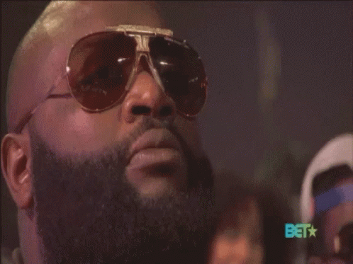 A Man With A Beard Wearing Sunglasses With The Bet Logo In The Background GIF