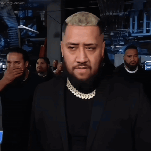 A Man With A Beard Wears A Black Suit And Gold Chain GIF