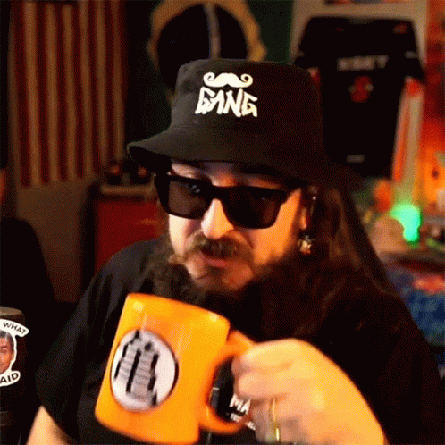 A Man With A Beard Wears A Hat That Says Gang GIF