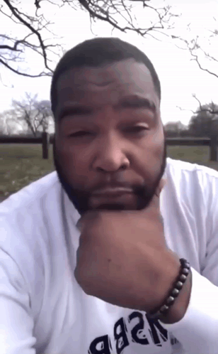 A Man With A Beard Wears A White Shirt That Says ' A & B ' On The Sleeve GIF