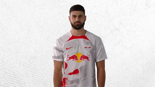 a man with a beard wears a white shirt with a red bull on it