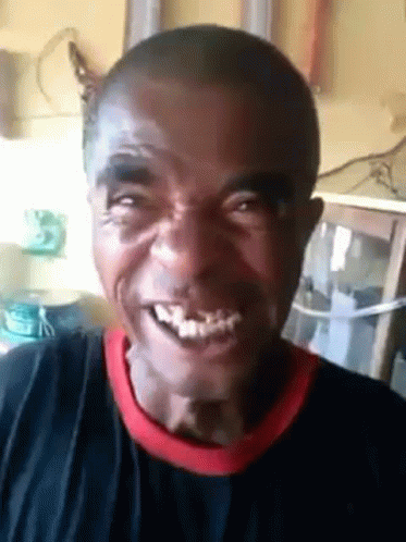 a man with a black shirt and a red collar is smiling and looking at the camera .