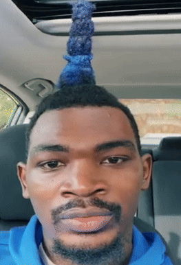 A Man With A Blue Mohawk And A Beard Looks At The Camera GIF