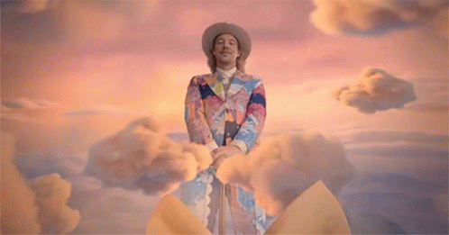 A Man With A Bow On His Head Stands Next To A Woman In A Yellow Dress GIF