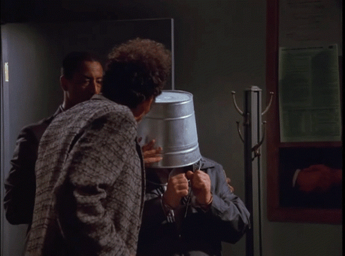 A Man With A Bucket On His Head Is Talking To Another Man With The Words Tell The World My Story Below Him GIF