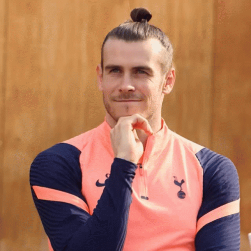 A Man With A Bun On His Head Is Wearing A Pink Shirt With The Letters Tottenham On It GIF