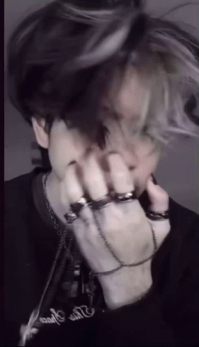 A Man With A Bunch Of Rings On His Hands Is Covering His Face . GIF