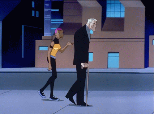A Man With A Cane And A Woman With Pink Hair Walk Down A Street GIF